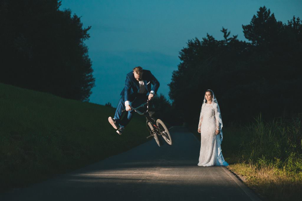 Groom jumping on the bmx bride beside