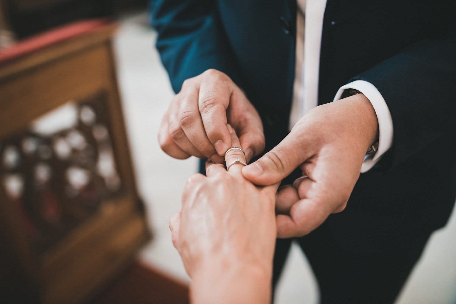 groom puts the wedding ring on bride finger