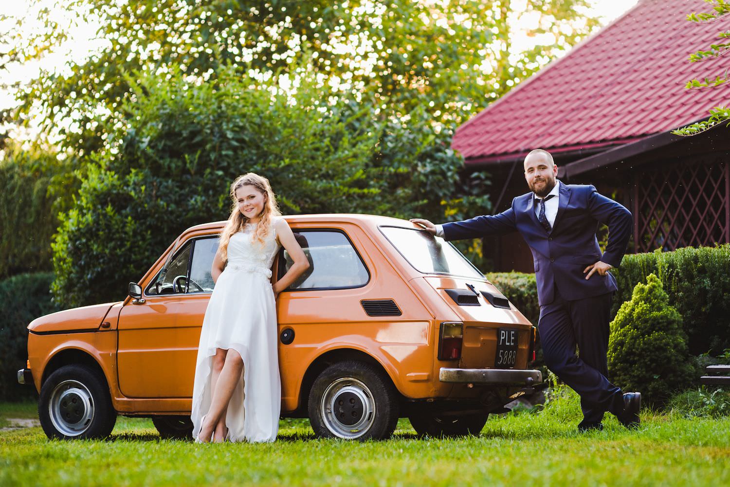 bride and groom at "maluch" orange old school car