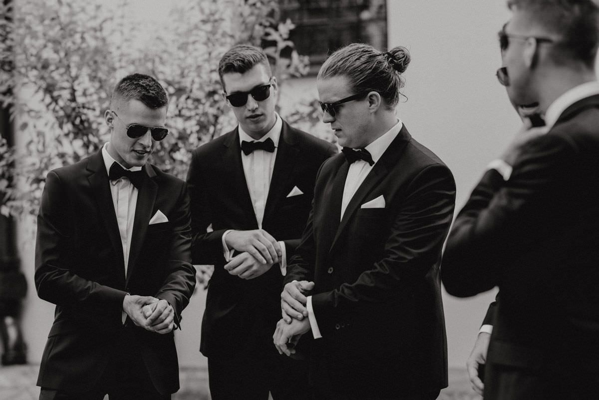 groomsmen in black sunglasses hold their hands