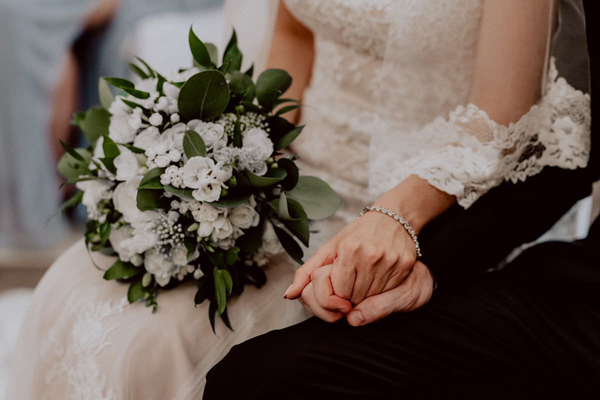 bride holds hand of her man keeps flowers in other hand