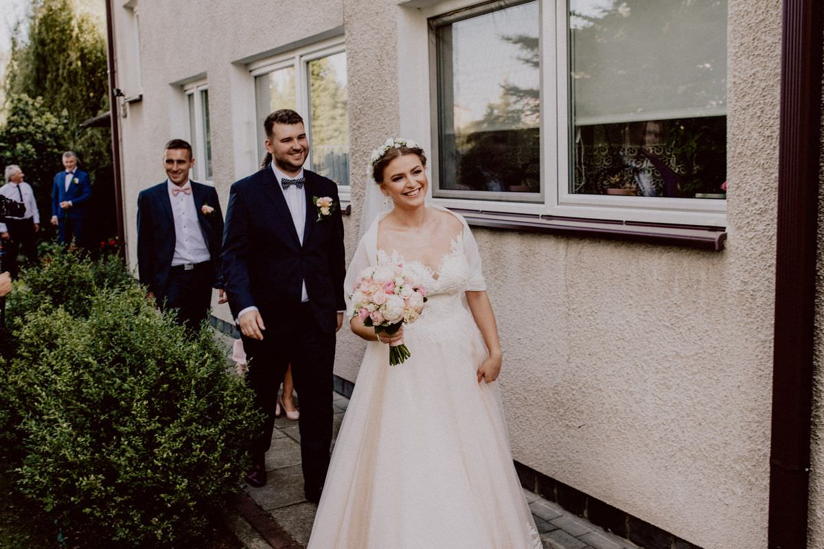 bride is smiling in front of the house