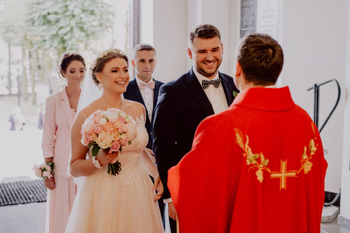 priest welcomes the married couple into church