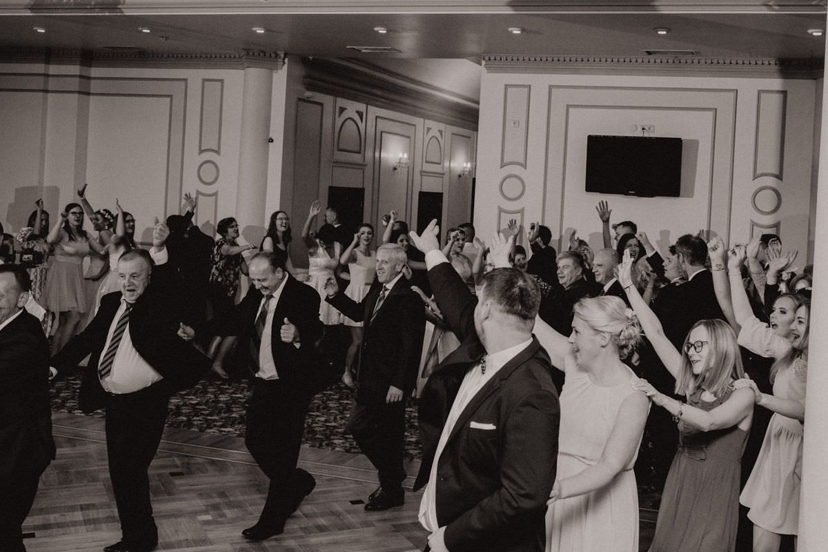 all people on wedding on dance floor with hands in the air