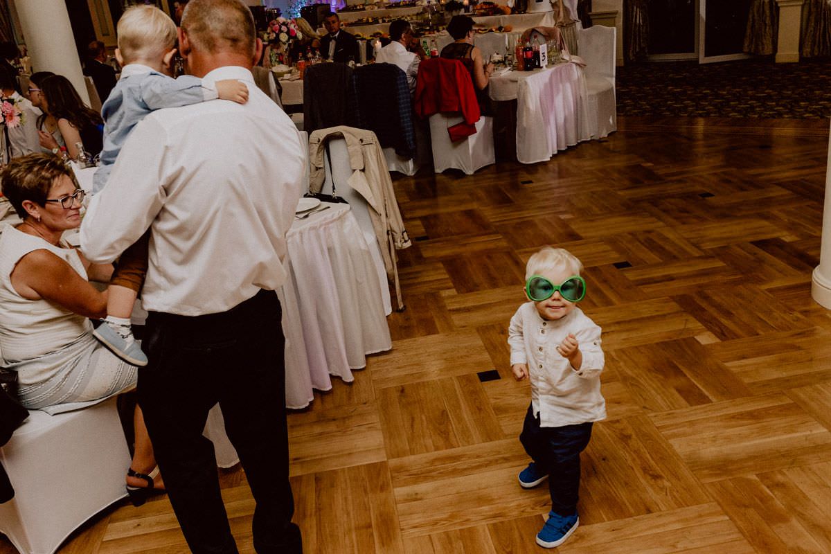 little kid with big green glasses looks like playing the guitar