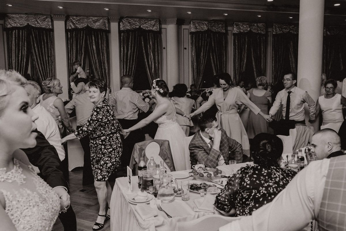 people on wedding party dancing between tables black and white