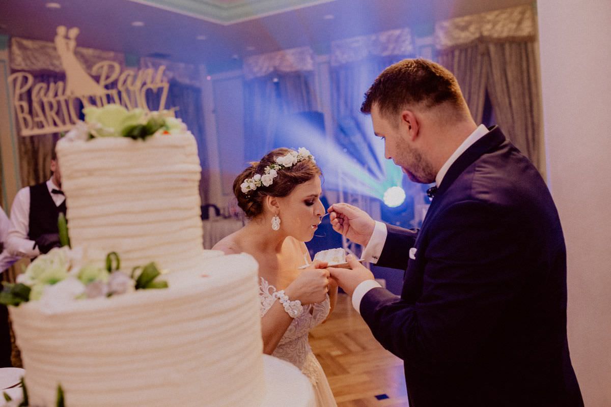 the groom feeds the bride a wedding cake