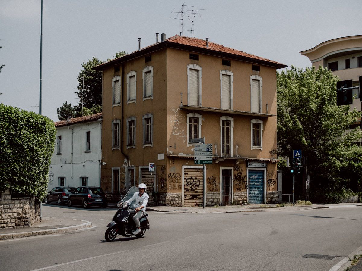 bergamo street and man riding on vespa
